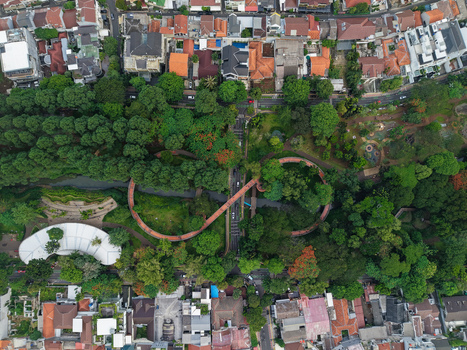 Aerial view of Tebet Eco Park featuring its iconic infinity bridge surrounded by lush trees and urban residential rooftops in Kecamatan Tebet Daerah Khusus Ibukota Indonesia. Aerial view of Tebet Eco Park featuring its iconic infinity bridge surrounded by lush trees and urban residential rooftops in Kecamatan Tebet Daerah Khusus Ibukota Indonesia.