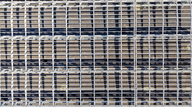 Aerial view of a metal hall structure with repeating grid patterns and long shadows cast on the ground in Kovin Vojvodina Serbia. Aerial view of a metal hall structure with repeating grid patterns and long shadows cast on the ground in Kovin Vojvodina Serbia.