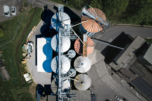Aerial view of the Moulin de la Vaux industrial silos and grain storage facility with metallic structures and surrounding roads in Aubonne Vaud Switzerland. Aerial view of the Moulin de la Vaux industrial silos and grain storage facility with metallic structures and surrounding roads in Aubonne Vaud Switzerland.