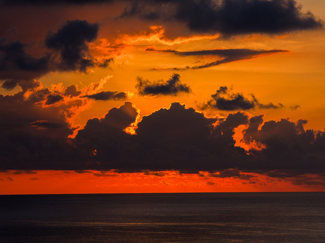 Aerial view of a dramatic sunset over the Indian Ocean at Mauritius Island with dark clouds backlit by vibrant orange and red light Moka District Mauritius. Aerial view of a dramatic sunset over the Indian Ocean at Mauritius Island with dark clouds backlit by vibrant orange and red light Moka District Mauritius.