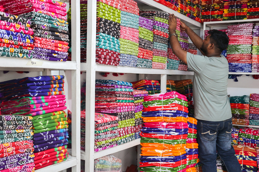 Narayanganj Bangladesh 29 March 2026 View of a man carefully organizing stacks of vibrant patterned textiles on shelves a riot of colors and textures. Narayanganj Bangladesh 29 March 2026 View of a man carefully organizing stacks of vibrant patterned textiles on shelves a riot of colors and textures.