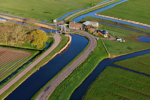 Aerial view of the historic wipbrug drawbridge and a traditional house surrounded by canals and green polder fields in Spanbroek North Holland Netherlands.