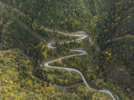 Aerial view of a winding mountain road through the dense autumn forest of the Pyrenees in Spain. Aerial view of a winding mountain road through the dense autumn forest of the Pyrenees in Spain.