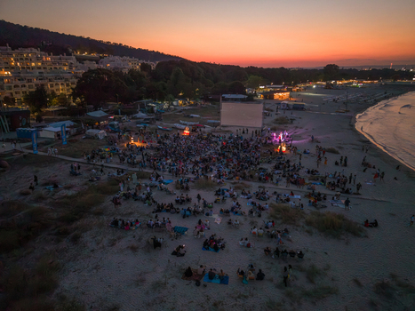 Varna Bulgaria 04 August 2026 Aerial view of Asparuhovo beach during an outdoor cinema event at sunset with a large crowd gathered on the sand.