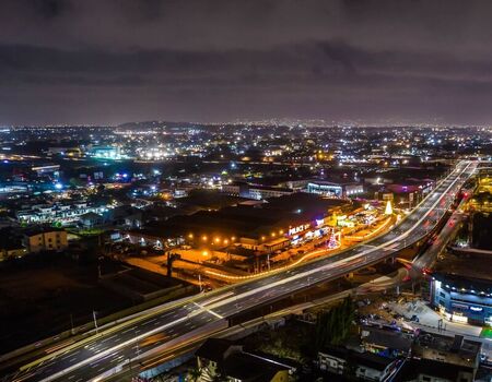 Aerial view of a highway with light trails at night surrounded by illuminated urban buildings and city lights in Ghana. Aerial view of a highway with light trails at night surrounded by illuminated urban buildings and city lights in Ghana.