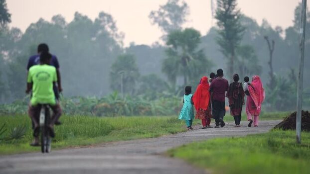 View of people walking on a rural road in Bogura Bangladesh.