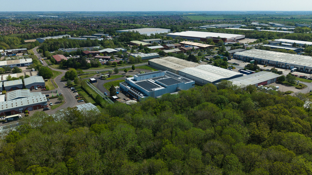 Aerial view of a modern data centre with solar panels on the roof surrounded by lush green trees and industrial warehouses in Wellingborough England United Kingdom. Aerial view of a modern data centre with solar panels on the roof surrounded by lush green trees and industrial warehouses in Wellingborough England United Kingdom.