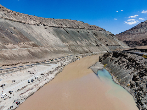 Aerial view of the confluence of the Indus and Zanskar rivers showing the meeting of muddy and turquoise waters amidst rugged mountains and a road in Ladakh Division Ladakh India. Aerial view of the confluence of the Indus and Zanskar rivers showing the meeting of muddy and turquoise waters amidst rugged mountains and a road in Ladakh Division Ladakh India.