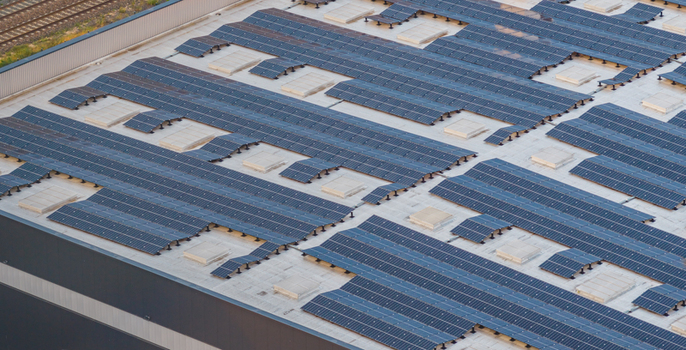 Aerial view of industrial rooftop solar panels and HVAC systems on a modern logistics warehouse in Alixan Auvergne Rhone Alpes France.