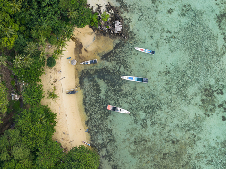 Aerial view of boats resting on the shore of Karina Beach where the turquoise water meets the lush green vegetation Karimunjawa Central Java Indonesia.