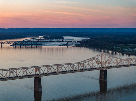 Aerial view of steel truss bridges spanning the Ohio River under a vibrant sunset sky with pink and orange hues Louisville Kentucky United States. Aerial view of steel truss bridges spanning the Ohio River under a vibrant sunset sky with pink and orange hues Louisville Kentucky United States.