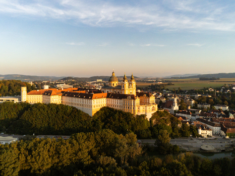Aerial view of the historic Melk Abbey perched on a rocky outcrop overlooking the town of Melk and the surrounding landscape during golden hour in Melk Niederosterreich Austria. Aerial view of the historic Melk Abbey perched on a rocky outcrop overlooking the town of Melk and the surrounding landscape during golden hour in Melk Niederosterreich Austria.