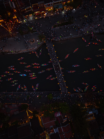 Aerial view of many small boats with colorful lanterns floating on the river at night under a bridge in Vietnam. Aerial view of many small boats with colorful lanterns floating on the river at night under a bridge in Vietnam.