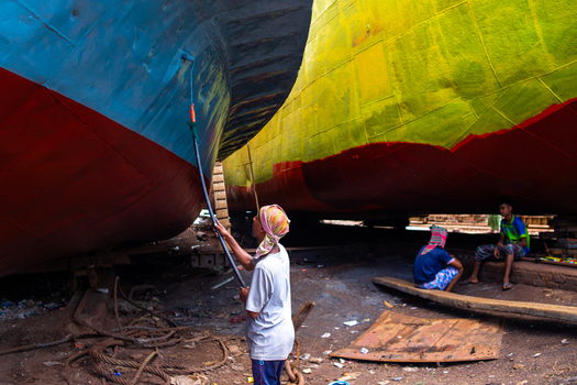 Keraniganj Bangladesh 04 September 2024 View of workers painting large ship hulls with vibrant colors at Shipyard Dhaka featuring industrial textures and manual labor in the shipyard.
