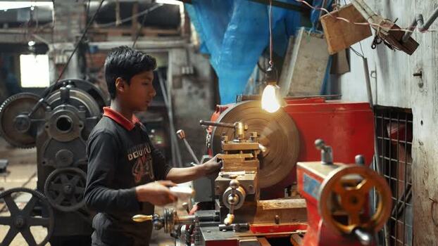 View of a young worker operating a lathe machine in a workshop Bangladesh.