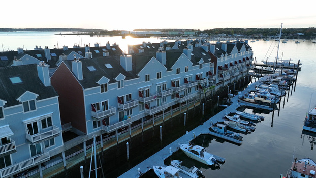 Aerial view of Portland waterfront and fishing piers with residential buildings on stilts moored boats and calm water at sunset in Portland Maine United States.