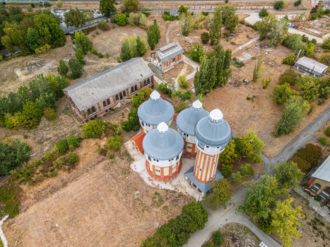Aerial view of the restored air distillery towers and derelict brick industrial buildings at the historic Obuda gasworks in Budapest Hungary surrounded by dry grounds and trees. Aerial view of the restored air distillery towers and derelict brick industrial buildings at the historic Obuda gasworks in Budapest Hungary surrounded by dry grounds and trees.