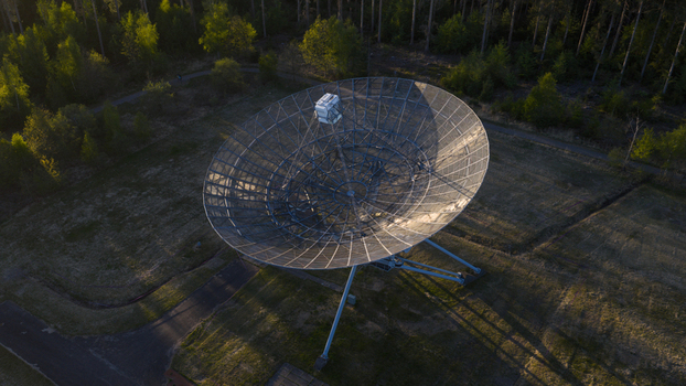 Aerial view of the Westerbork Synthesis Radio Telescope dish surrounded by lush forest during golden hour in Zwiggelte Drenthe Netherlands. Aerial view of the Westerbork Synthesis Radio Telescope dish surrounded by lush forest during golden hour in Zwiggelte Drenthe Netherlands.