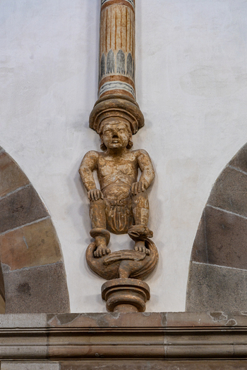 View of an intricate stone carving of a squatting figure supporting a column inside the historic Ribe Cathedral Ribe Denmark. View of an intricate stone carving of a squatting figure supporting a column inside the historic Ribe Cathedral Ribe Denmark.