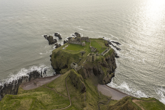 Aerial view of the medieval ruins of Dunnottar Castle perched on a rocky headland above the North Sea in Stonehaven Scotland United Kingdom. Aerial view of the medieval ruins of Dunnottar Castle perched on a rocky headland above the North Sea in Stonehaven Scotland United Kingdom.