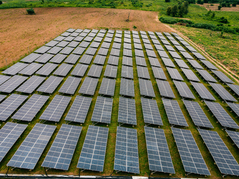 Aerial view of a large solar farm with rows of photovoltaic panels installed in a grassy field in Ogun State Nigeria.