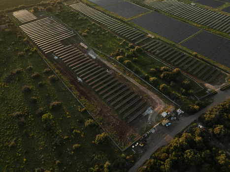 Aerial view of a large solar farm with rows of photovoltaic panels surrounded by green fields and trees during sunset in Augusta Sicily Italy. Aerial view of a large solar farm with rows of photovoltaic panels surrounded by green fields and trees during sunset in Augusta Sicily Italy.