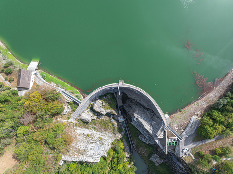 Aerial view of Barrage de Montsalvens dam with its curved concrete wall surrounded by lush forest and turquoise reservoir waters in Chatel sur Montsalvens Fribourg Switzerland. Aerial view of Barrage de Montsalvens dam with its curved concrete wall surrounded by lush forest and turquoise reservoir waters in Chatel sur Montsalvens Fribourg Switzerland.