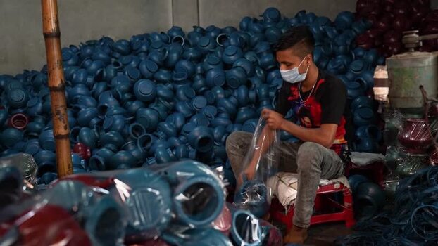 View of a worker packing blue plastic pots in Bogura Bangladesh. View of a worker packing blue plastic pots in Bogura Bangladesh.