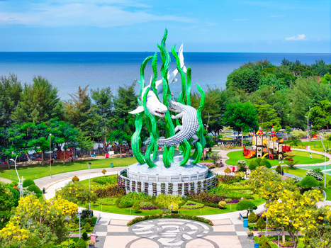 Aerial view of Suroboyo Monument featuring a shark and crocodile sculpture surrounded by lush greenery and flower beds in Suroboyo Park Kecamatan Bulak Jawa Timur Indonesia.