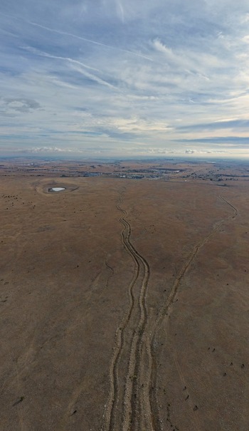 Aerial view of winding dirt tracks cutting through the dry open plains of the Colorado landscape under a vast sky in Golden Colorado United States.