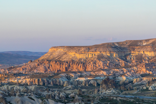 Aerial view of Rose Valley in Cappadocia featuring unique rock formations fairy chimneys and rugged terrain illuminated by the soft light of the golden hour in Goreme Nevsehir Turkiye. Aerial view of Rose Valley in Cappadocia featuring unique rock formations fairy chimneys and rugged terrain illuminated by the soft light of the golden hour in Goreme Nevsehir Turkiye.