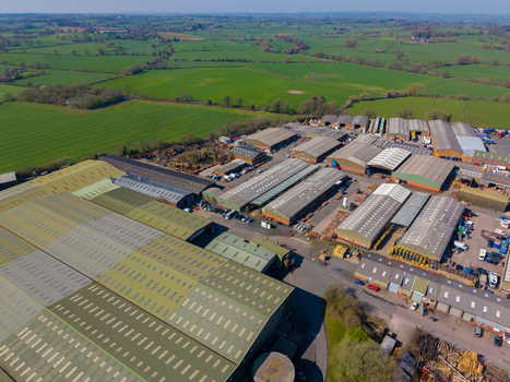 Aerial view of Ladfordfields Industrial Estate featuring rows of industrial warehouses with metal roofs surrounded by green fields in the rural landscape of Stafford England United Kingdom. Aerial view of Ladfordfields Industrial Estate featuring rows of industrial warehouses with metal roofs surrounded by green fields in the rural landscape of Stafford England United Kingdom.
