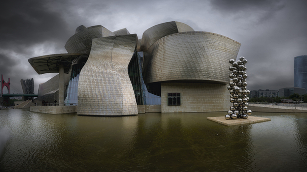 Bilbao Spain 08 June 2024 View of Guggenheim Museum Bilbao with its iconic titanium curves reflecting on the water under a dramatic cloudy sky.