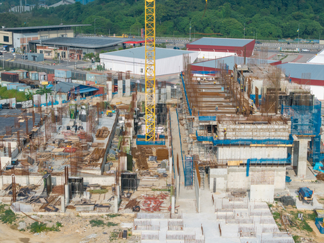 Bukit Tambun Malaysia 25 September 2026 Aerial view of a construction site featuring a tall yellow crane concrete foundations exposed rebar and workers on the building site. Bukit Tambun Malaysia 25 September 2026 Aerial view of a construction site featuring a tall yellow crane concrete foundations exposed rebar and workers on the building site.