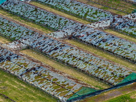 Aerial view of abandoned greenhouses with broken glass panels and moss growth on a grassy field Vilnius County Lithuania. Aerial view of abandoned greenhouses with broken glass panels and moss growth on a grassy field Vilnius County Lithuania.