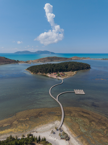 Aerial view of Zvernec Islands featuring the wooden bridge leading to the historic monastery surrounded by Narta Lagoon under a clear blue sky in Vlore Vlore County Albania. Aerial view of Zvernec Islands featuring the wooden bridge leading to the historic monastery surrounded by Narta Lagoon under a clear blue sky in Vlore Vlore County Albania.
