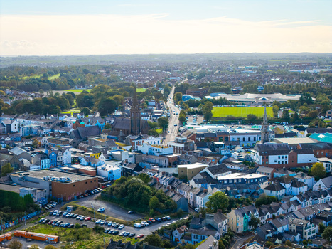 Aerial view of Bangor Harbour and Town with historic stone churches dense residential rooftops and green spaces Bangor Northern Ireland United Kingdom.