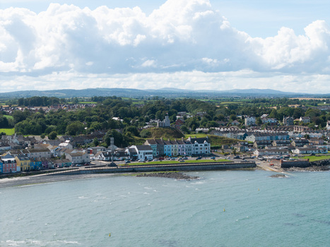 Aerial view of Donaghadee Harbour with its historic motte colorful waterfront buildings and surrounding coastline under a bright sky in Donaghadee Northern Ireland United Kingdom. Aerial view of Donaghadee Harbour with its historic motte colorful waterfront buildings and surrounding coastline under a bright sky in Donaghadee Northern Ireland United Kingdom.