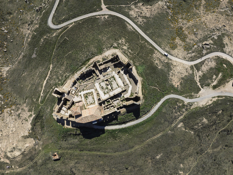 Aerial view of the historic Castle Montearagon ruins featuring stone walls and courtyards situated on a hilltop surrounded by winding roads in Quicena Aragon Spain.