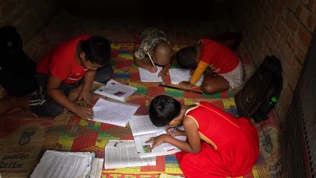 View of children studying on a mat in Bogura Bangladesh.