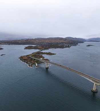 Aerial view of the Skye Bridge spanning the sea between islands under an overcast sky Isle of Skye Scotland United Kingdom.