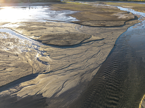 Aerial view of sandy riverbed with intricate water patterns and textures under golden hour light in Poland. Aerial view of sandy riverbed with intricate water patterns and textures under golden hour light in Poland.