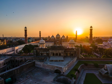 Aerial view of the historic Badshahi Mosque with its iconic domes and minarets illuminated by the warm golden light of sunset in Lahore Punjab Pakistan. Aerial view of the historic Badshahi Mosque with its iconic domes and minarets illuminated by the warm golden light of sunset in Lahore Punjab Pakistan.