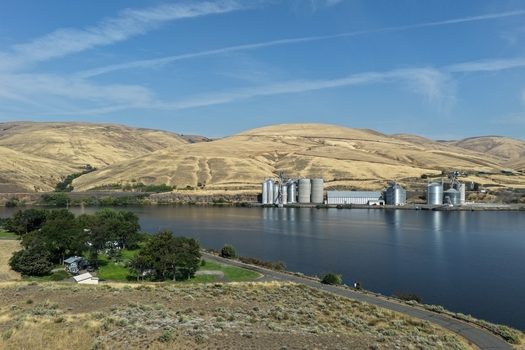 Aerial view of grain silos situated along the riverbank with rolling golden hills in the background in Whitman County Washington United States. Aerial view of grain silos situated along the riverbank with rolling golden hills in the background in Whitman County Washington United States.