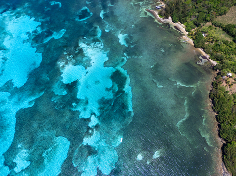 Aerial view of the turquoise coral reefs and lush tropical coastline of Guanaja Bay Islands Department Honduras. Aerial view of the turquoise coral reefs and lush tropical coastline of Guanaja Bay Islands Department Honduras.