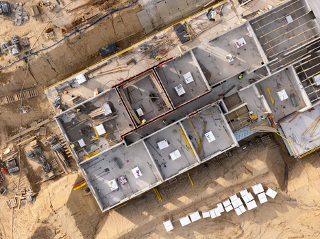 Aerial view of a construction site with concrete building foundations workers in safety vests construction materials and excavated earth in Gdansk Poland. Aerial view of a construction site with concrete building foundations workers in safety vests construction materials and excavated earth in Gdansk Poland.