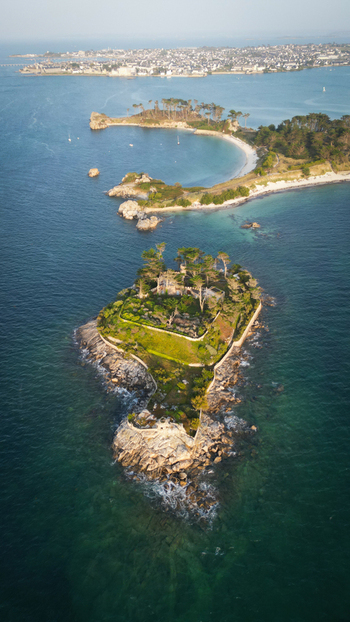Aerial view of the Pointe de Perharidy casting a serene emerald and sapphire jewel tone across the waters standing in stately isolation Roscoff Finistere France.