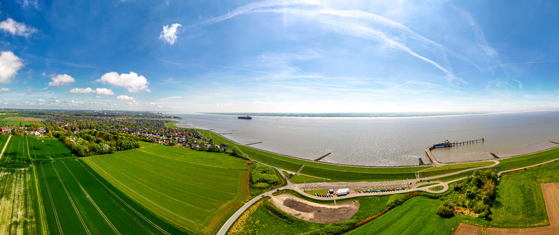 Brunsbuttel Germany 30 May 2025 Aerial view of the town of Brunsbuttel along the Elbe river featuring green fields a coastal dike and a pier. Brunsbuttel Germany 30 May 2025 Aerial view of the town of Brunsbuttel along the Elbe river featuring green fields a coastal dike and a pier.