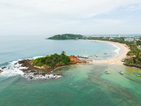 Aerial view of Parrot Rock and the sandy coastline with turquoise waters and palm trees in Mirissa Southern Province Sri Lanka. Aerial view of Parrot Rock and the sandy coastline with turquoise waters and palm trees in Mirissa Southern Province Sri Lanka.