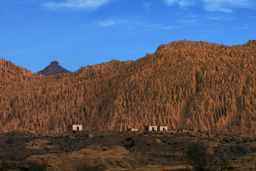 View of the unique eroded rock formations of Hingol National Park with small buildings in the foreground under a clear blue sky in Awaran Balochistan Pakistan.